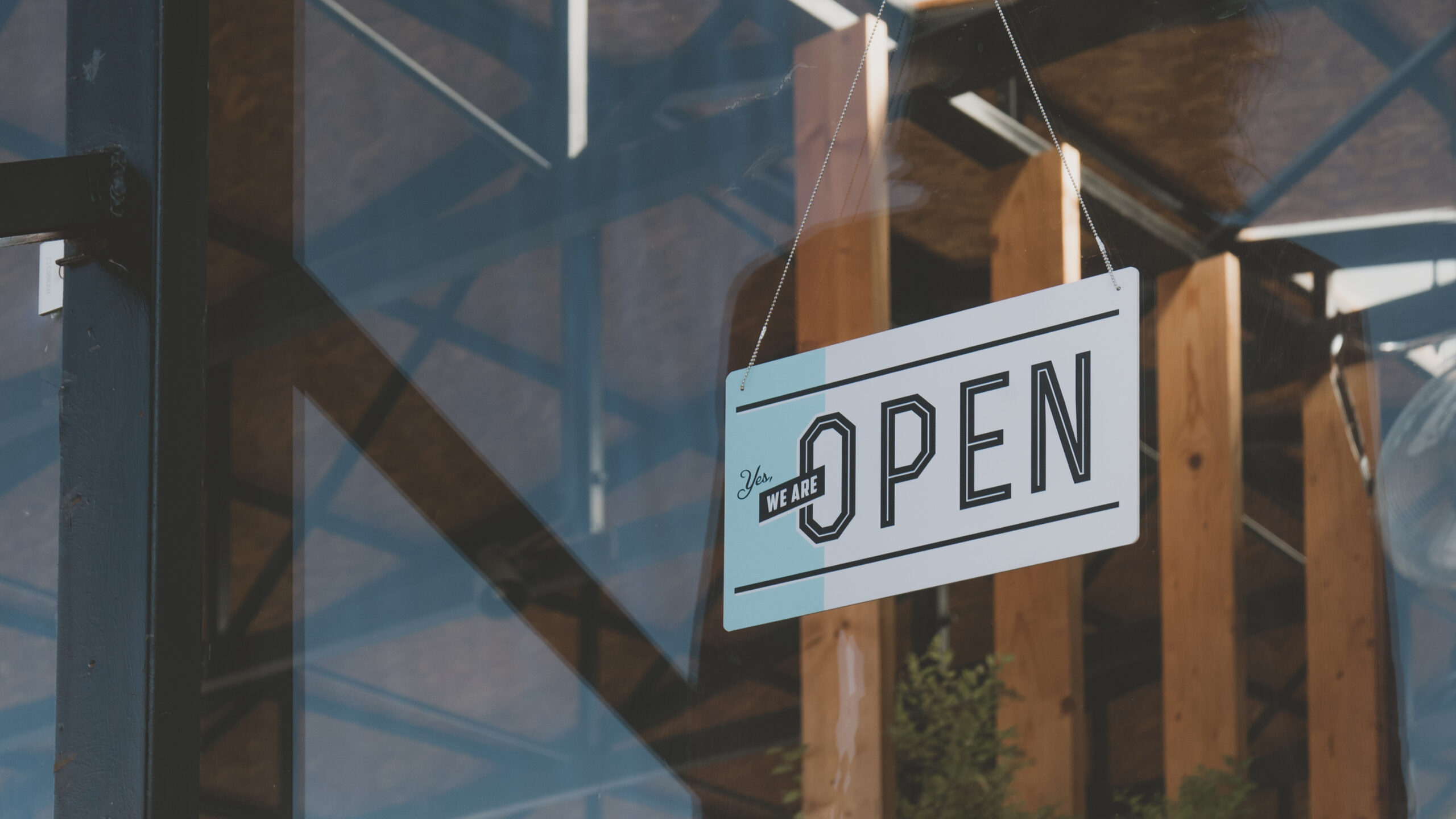 CU we are open sign hanging on the entrance door of a small cafe. Small business concept